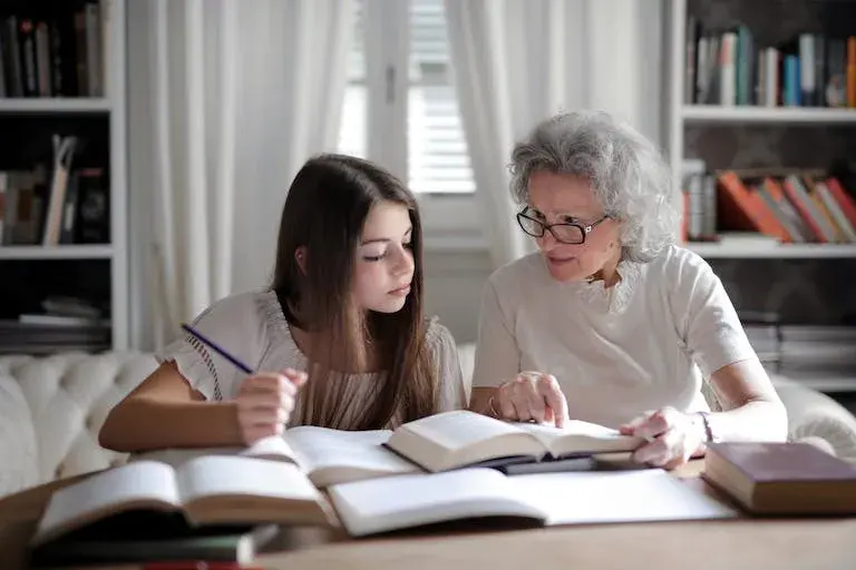 grandmother and granddaughter at table writing in many keepsake books